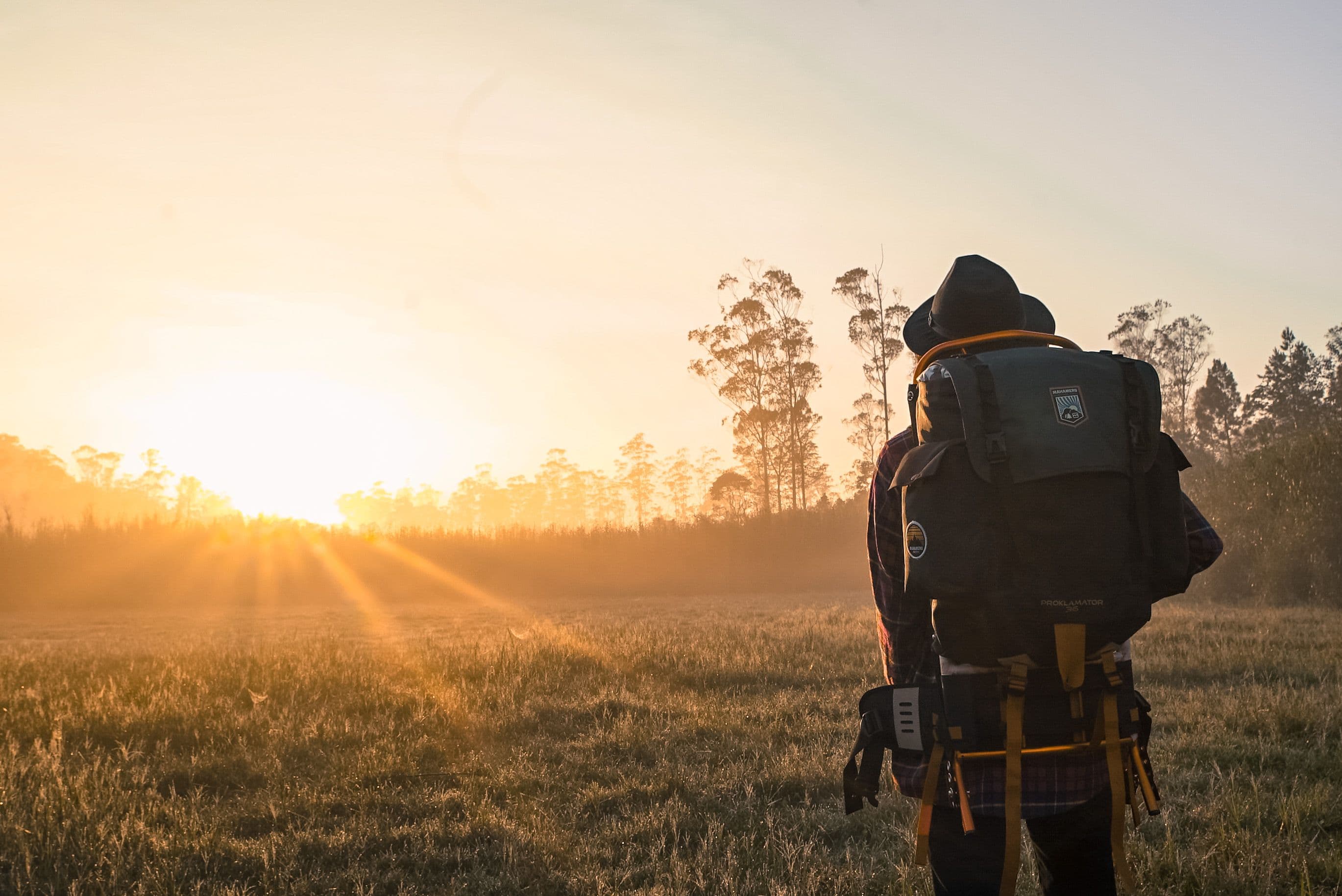 Randonneur avec un sac à dos face au lever du soleil en été